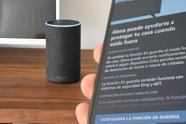 Amazon Echo al lado de un móvil mostrando la pantalla de la función En Guardia de Alexa