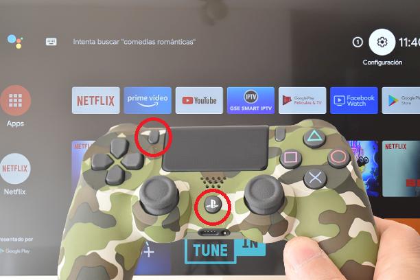 Mando de PS4 mostrando los botones para ponerlo en modo de sincronización. Detrás la pantalla de Inicio de una Smart TV Android