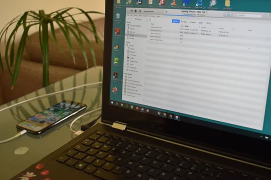 iPhone conectado a una laptop que muestra la interfaz de iTunes