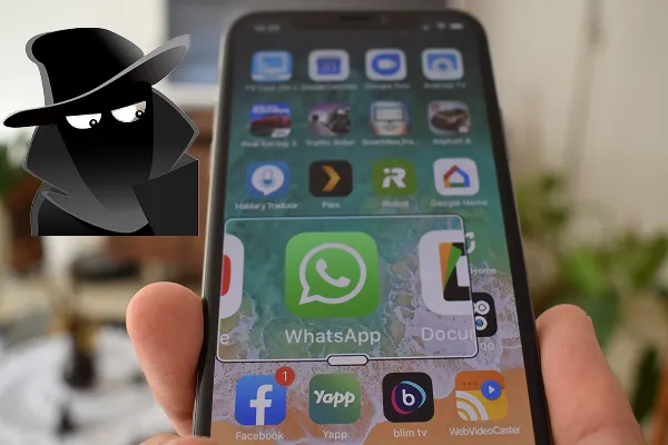 Ön planda WhatsApp simgesi olan bir akıllı telefonda casusluk yapan maskeli bir adamın görüntüsü
