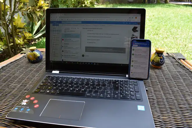La imagen muestra una laptop y un celular mostrando la bandeja de entrada de hotmail.