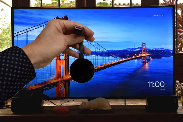 Chromecast ultra con un televisor smart de fondo. También se aprecia un altavoz inteligente google home.