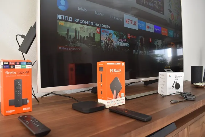 Dispositivos Fire TV, Mi Box y Chromecast al lado de un televisor