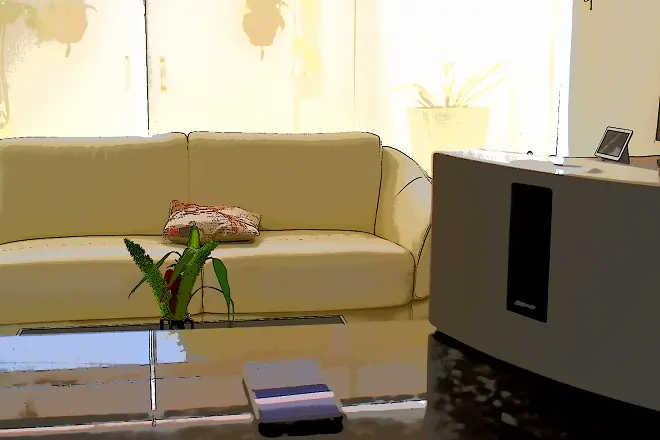 La imagen muestra un salón con el sistema Bose SoundTouch en primer plano, un smartphone a su lado y una pantalla inteligente Google Nest Hub detrás.
